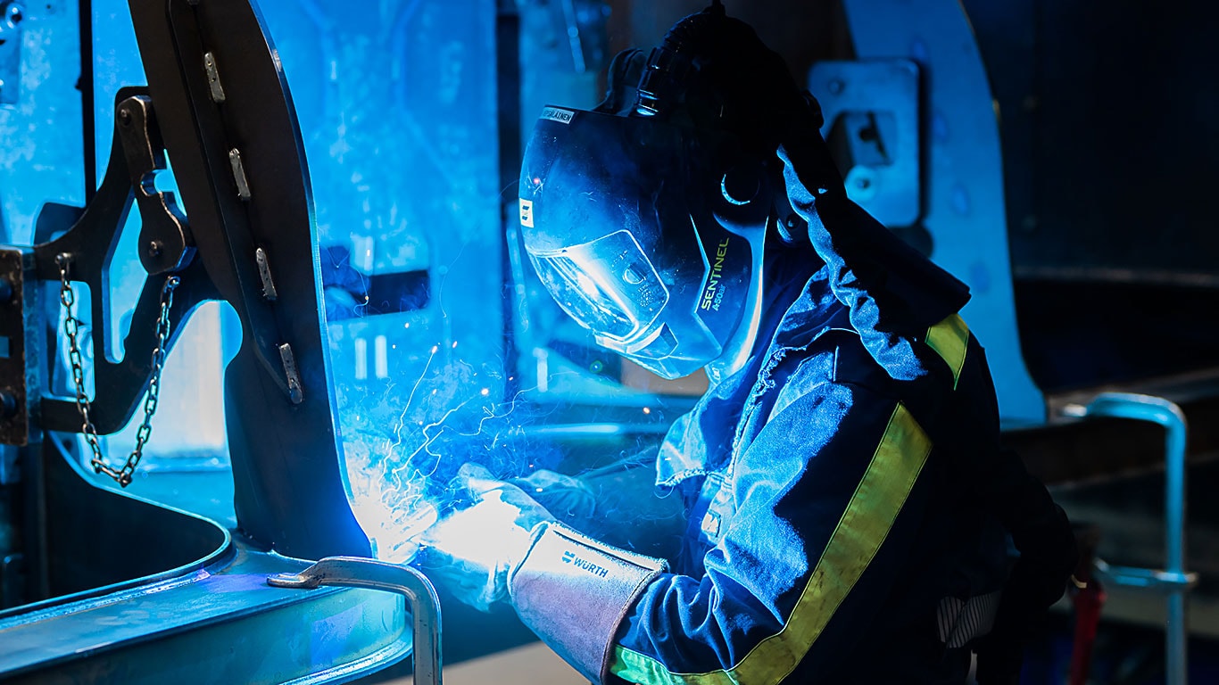 A person is welding a load space of a forest machine