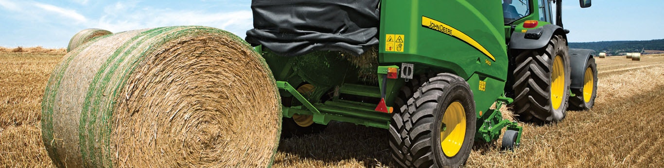 bale of hay being packaged by a tractor in a field