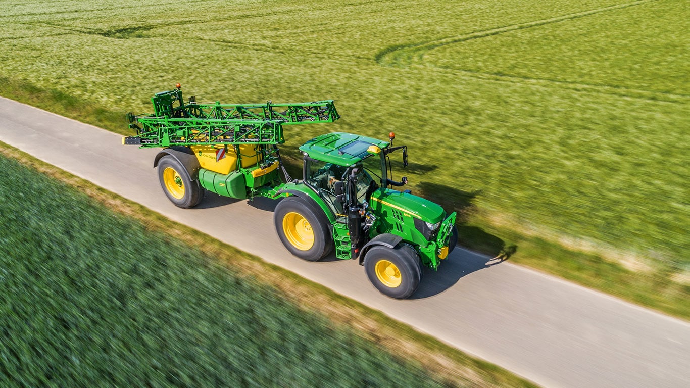 Aerial view of a tractor pulling trailed sprayer R732I between two fields