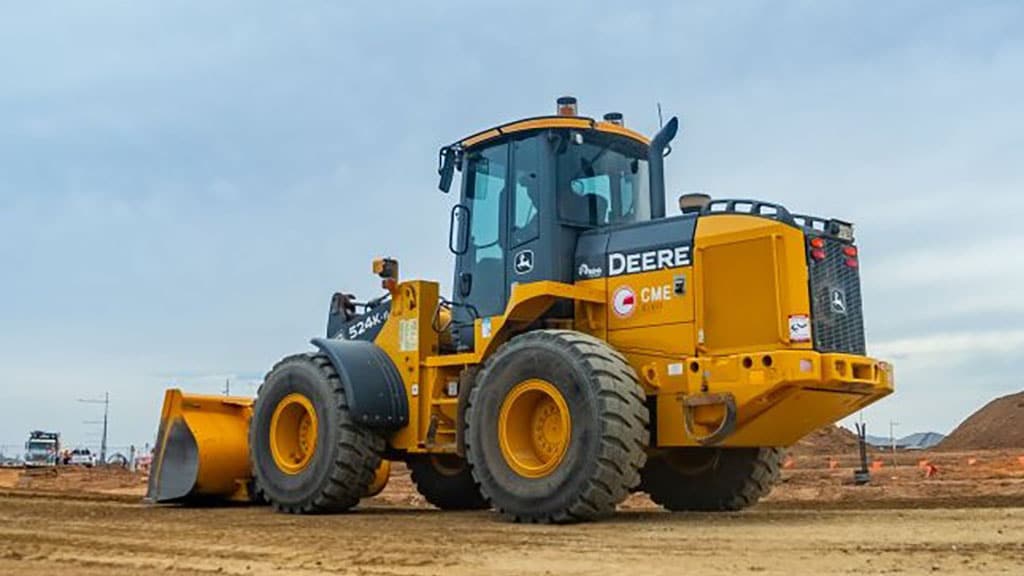 CME labeled 524k wheel loader on a dirt path with trucks in the background