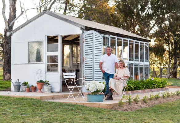 Sandy and Tim Palmer posing outside their a cute, white shed