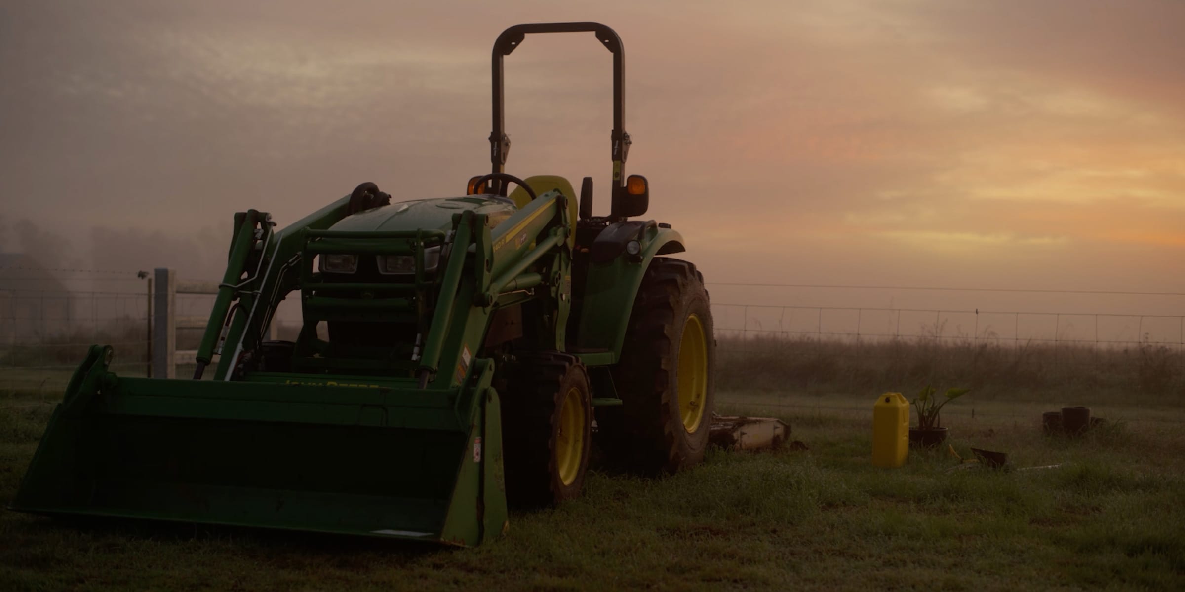 Front view shot of a John Deere utility tractor in a paddock at dusk