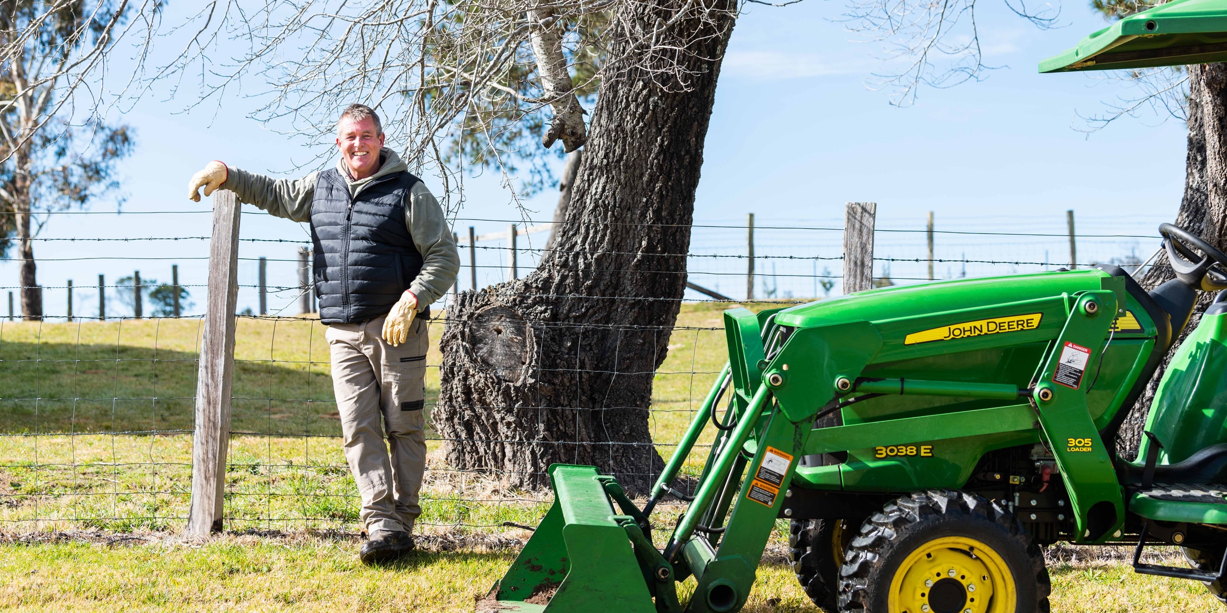 Tim Palmer leaning against a fence next to his John Deere Tractor