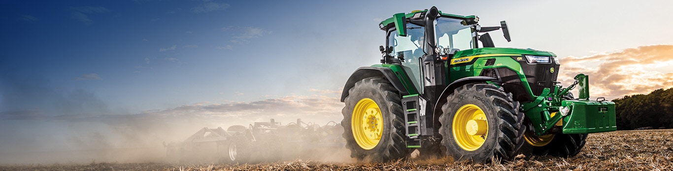 6R tractor tilling a field with dust surrounding it.