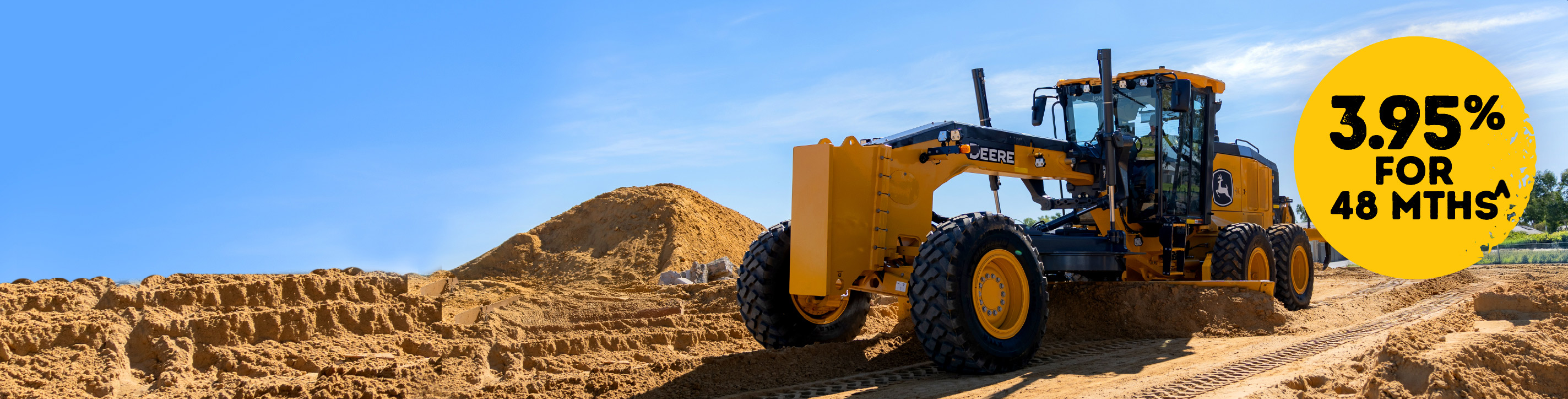 Motor grader on a dirt road with "3.95% for 48 months" written on thr right.