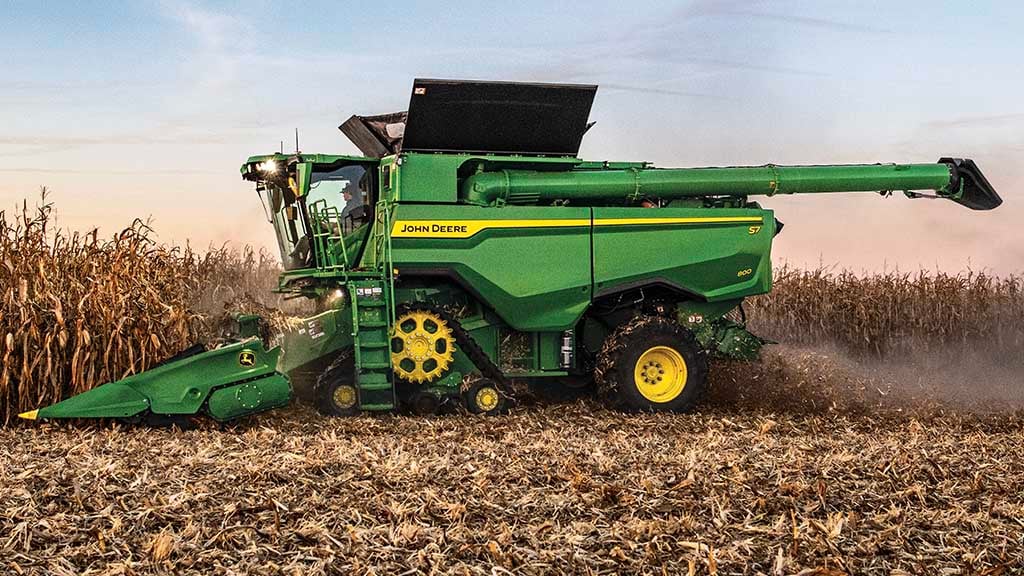 Side-view photo of a John Deere S7 Combine harvesting corn