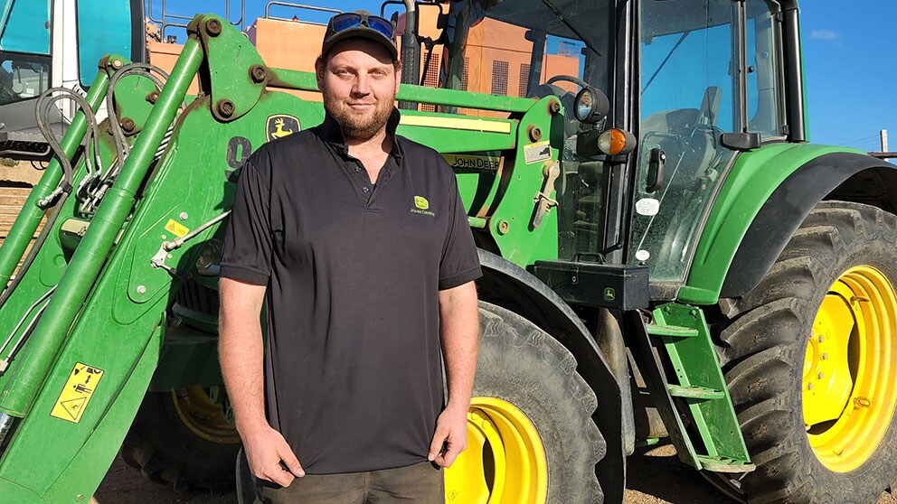 Logan Robinson standing in front of a John Deere tractor