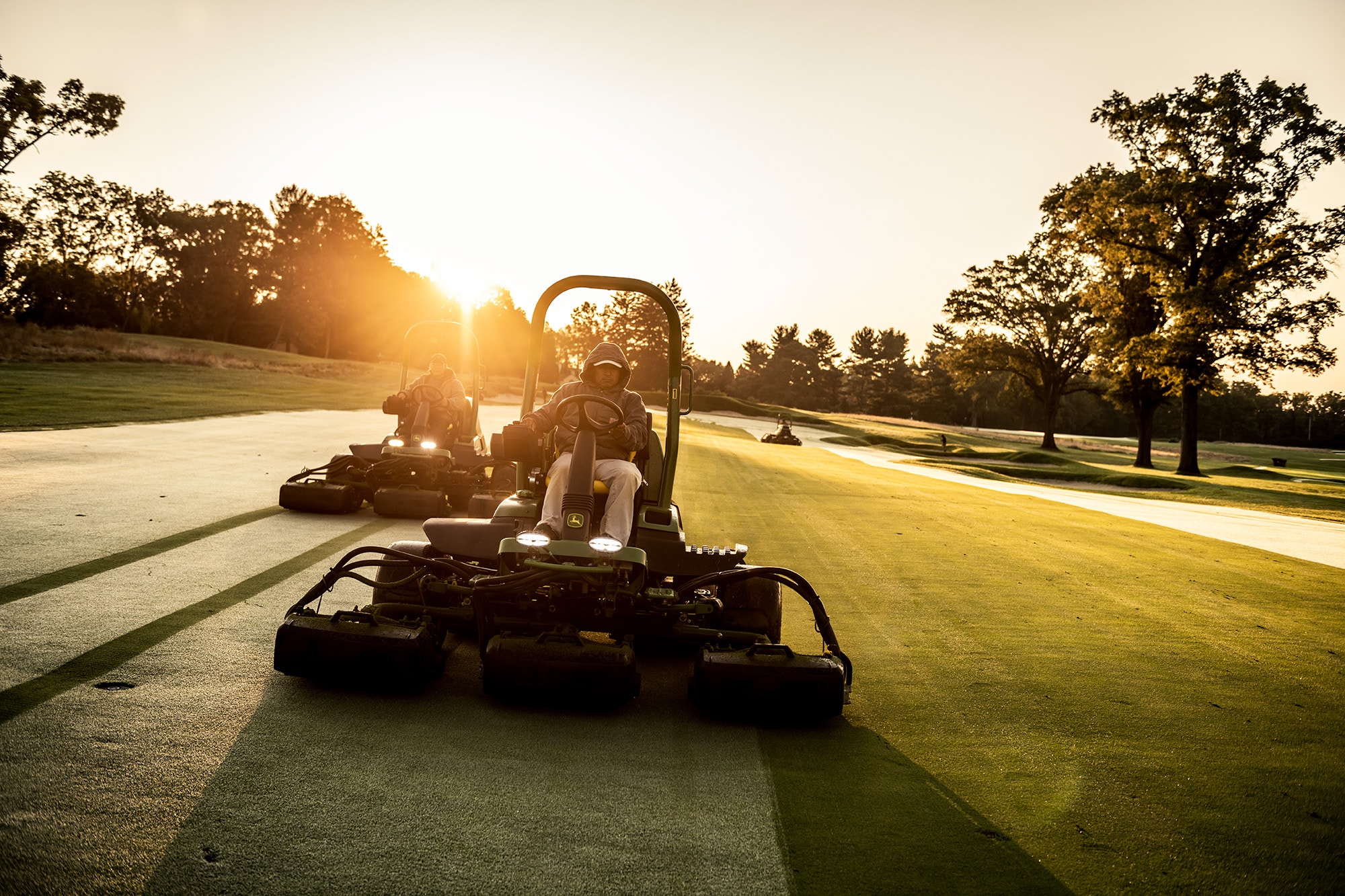 Three John Deere Fairway mowers in the early morning dew mowing.