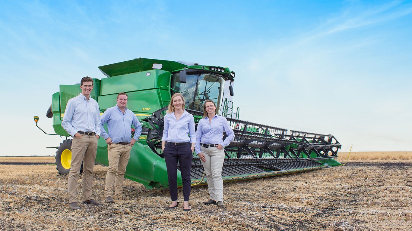 Graduate group standing in front of tractor