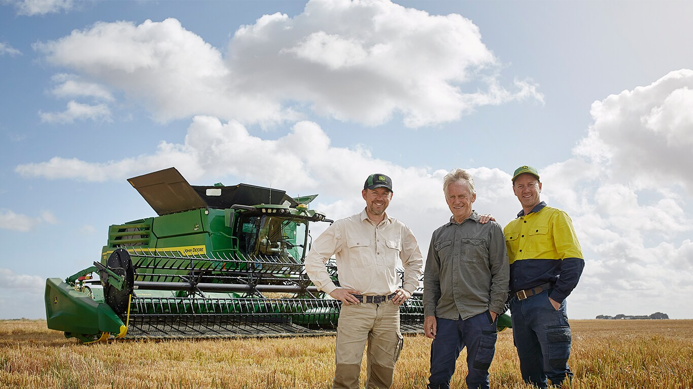Tim, Geoff and Luke Rethus standing in a field with their combine behind them