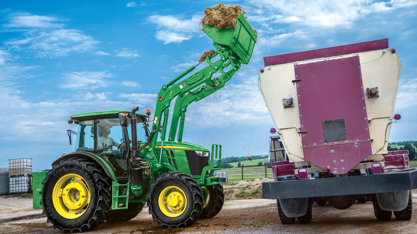 man in tractor using front end loader to fill another truck