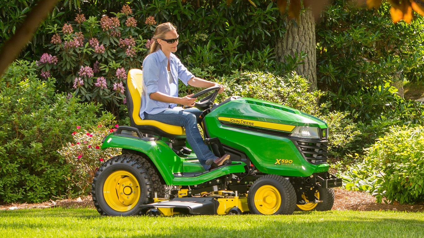 woman on x590 lawn tractor in yard