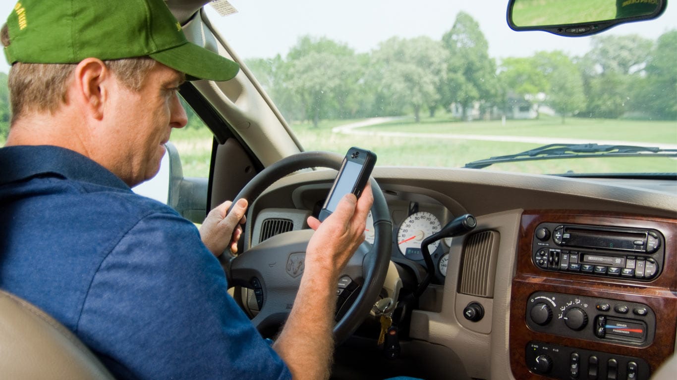 man utilizing his cell phone sitting in his vehicle to check on his machines with John Deere JDLink.