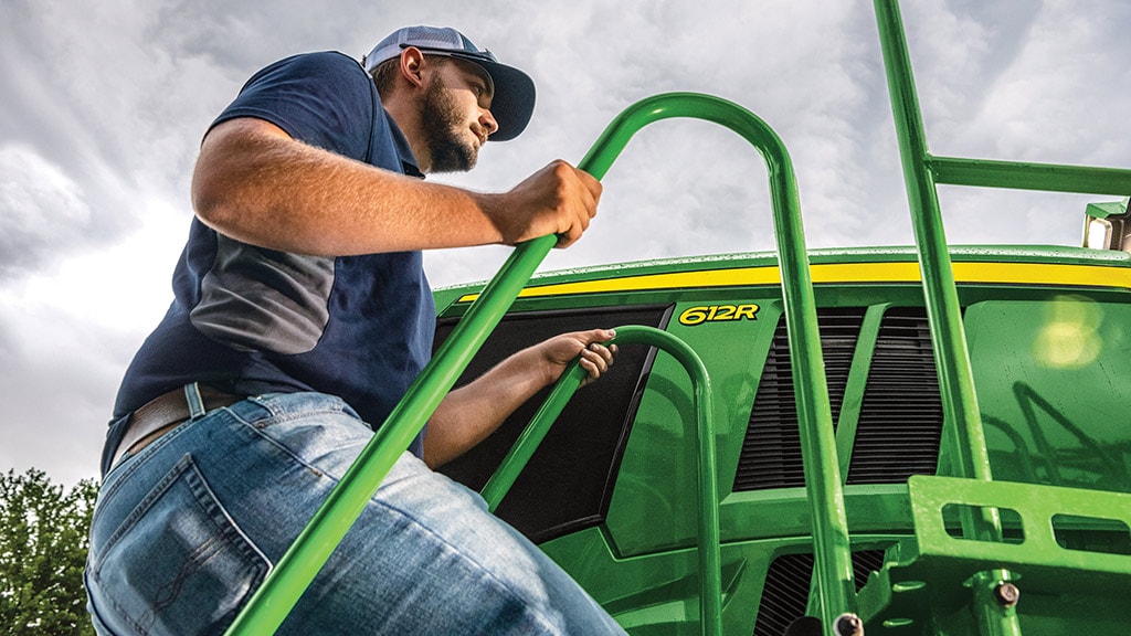 Operator climbing the ladder to the cab of a John Deere 612R Self-Propelled Sprayer.