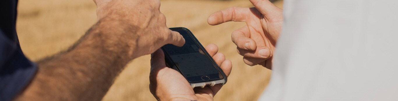 Two people using John Deere Precision Technology on a mobile phone in a field
