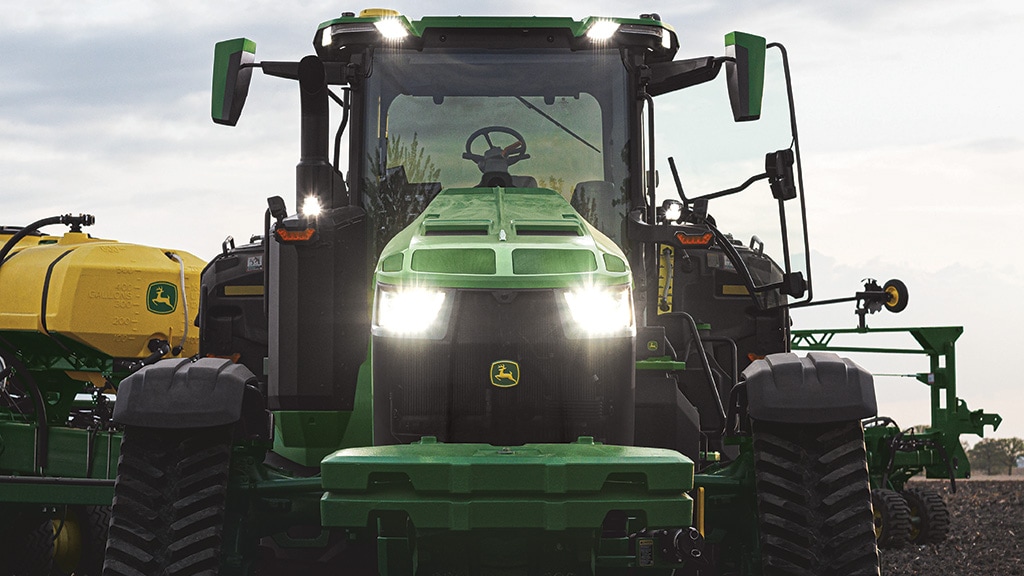 High-horsepower 8RX driving forward with lights on and a planter behind it.