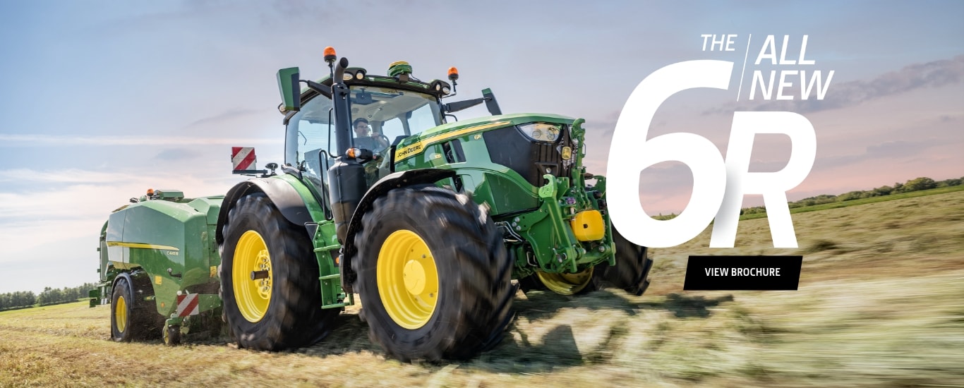 person driving John Deere tractor in a field