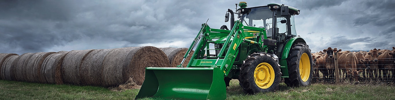 6 series utility tractor next to hay bales and cattle