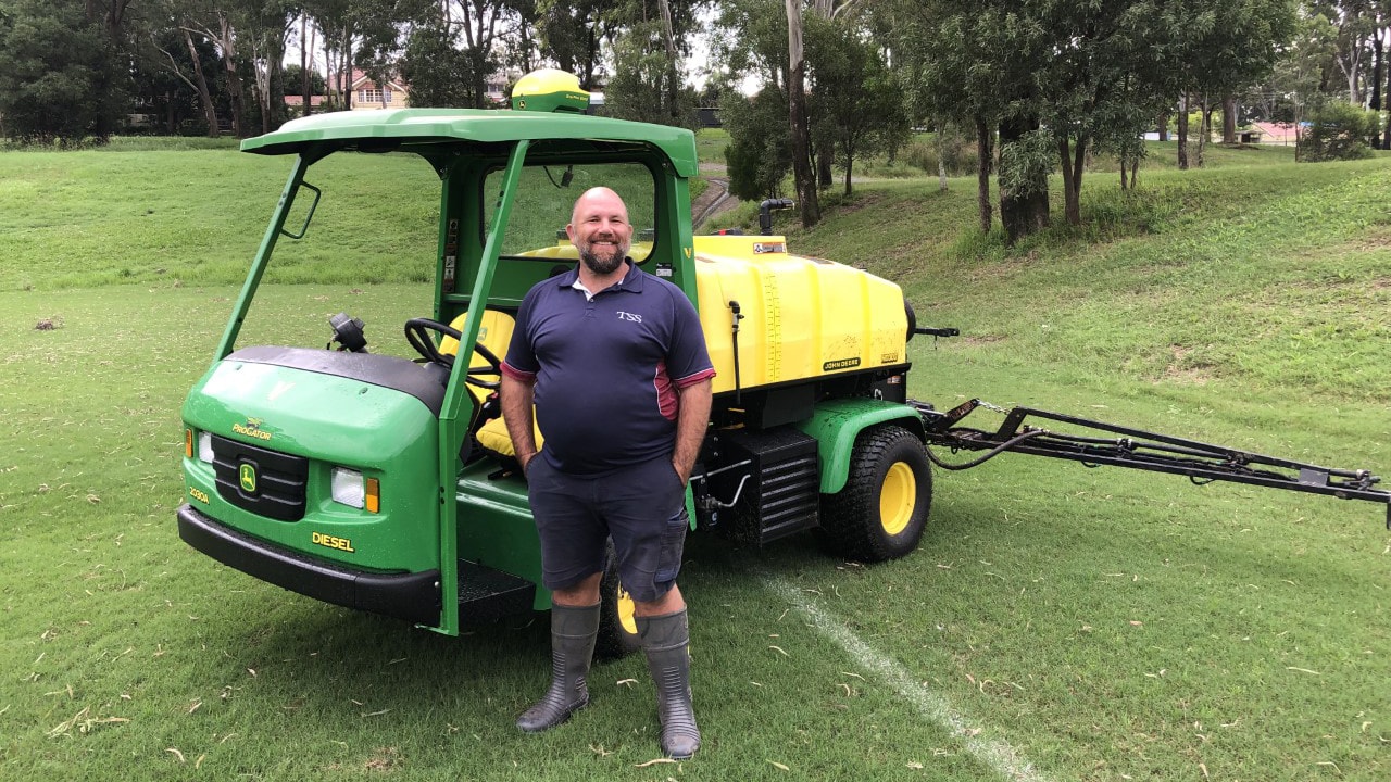 man smiling in front of a Deere 2030A ProGator